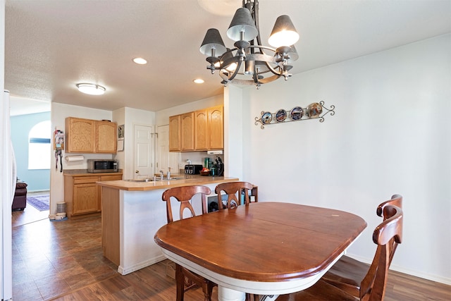 dining space featuring dark hardwood / wood-style floors, sink, and an inviting chandelier