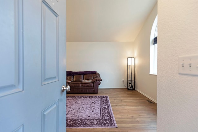 sitting room with vaulted ceiling, wood finished floors, visible vents, and baseboards