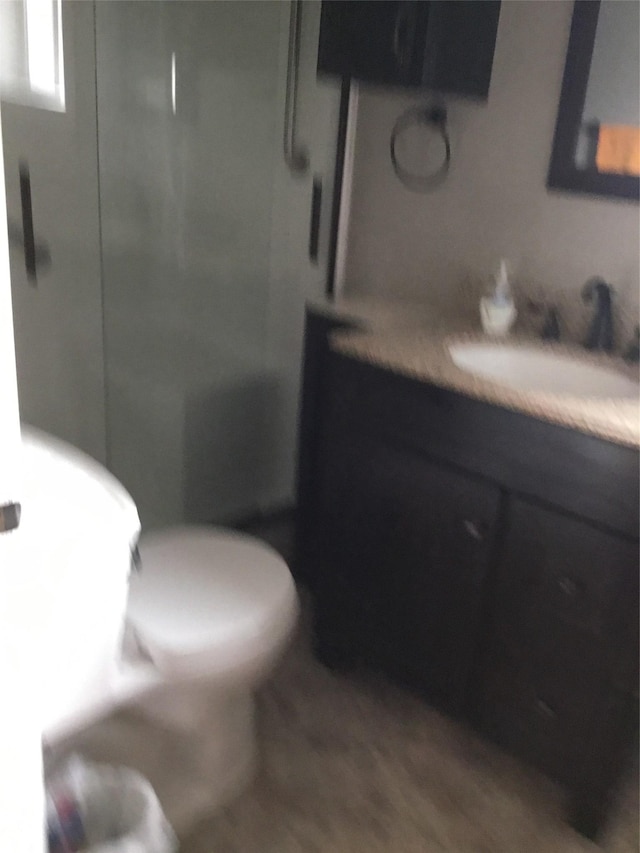 bathroom featuring hardwood / wood-style flooring, vanity, toilet, and a shower