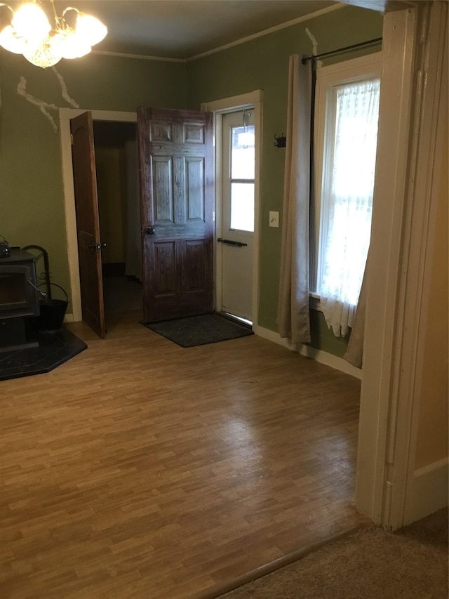 entrance foyer with wood-type flooring, ornamental molding, a wealth of natural light, and a notable chandelier