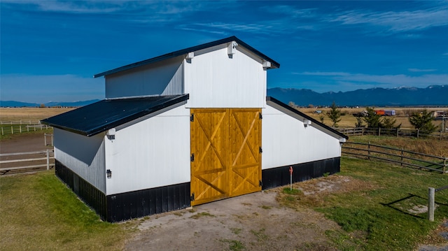 view of side of property featuring a mountain view, a rural view, and an outbuilding