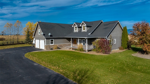 new england style home with a garage, a front yard, and a porch