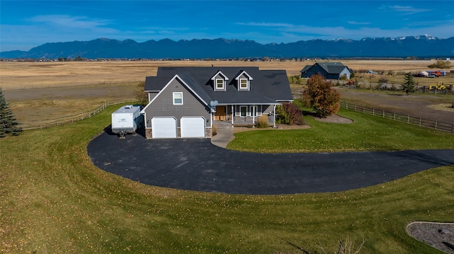 view of front of property featuring a rural view, a porch, a garage, a mountain view, and a front yard