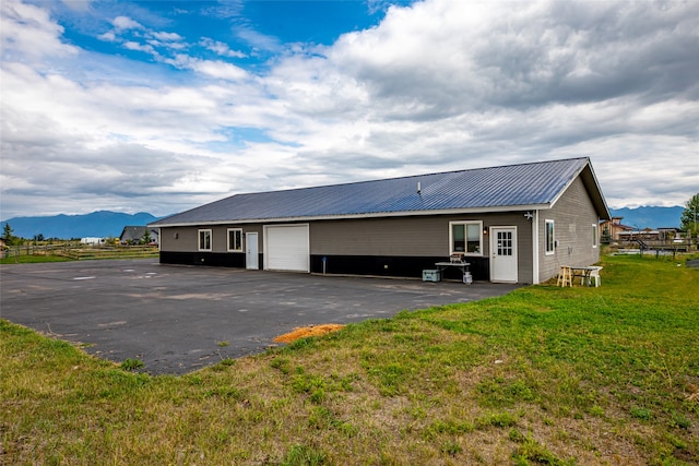 back of house featuring a mountain view, a yard, and a garage