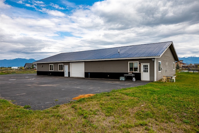 back of property with a lawn, a mountain view, and a garage