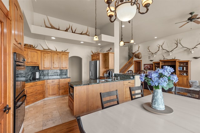 kitchen featuring stainless steel refrigerator, sink, ceiling fan, decorative light fixtures, and decorative backsplash