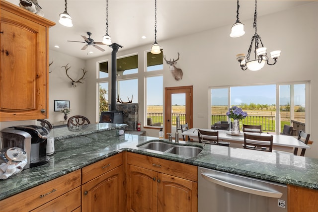 kitchen with sink, stainless steel dishwasher, decorative light fixtures, and a wood stove