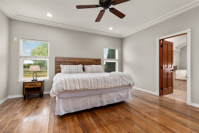 bedroom featuring crown molding, light hardwood / wood-style floors, ceiling fan, and ensuite bath