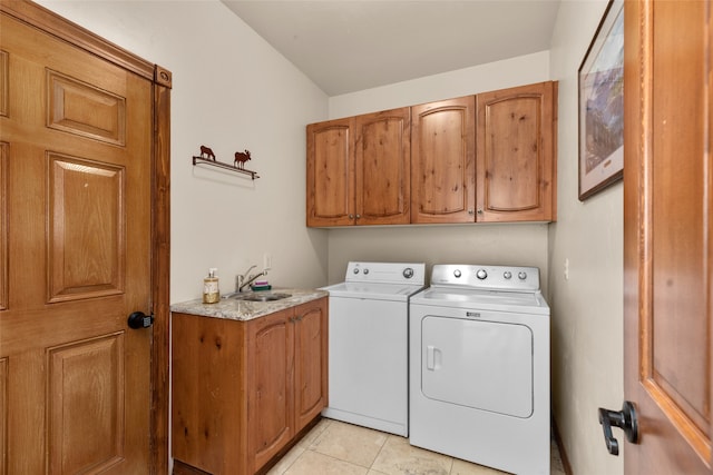 clothes washing area with cabinets, washing machine and dryer, light tile patterned floors, and sink