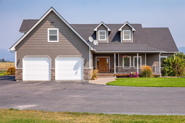 view of front of property with a porch, a front yard, and a garage