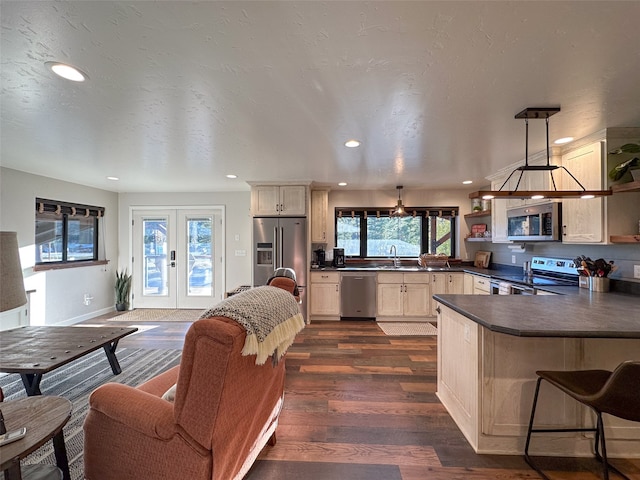 kitchen with french doors, kitchen peninsula, sink, pendant lighting, and appliances with stainless steel finishes