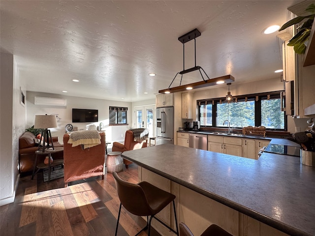 kitchen with sink, appliances with stainless steel finishes, a wall mounted air conditioner, dark hardwood / wood-style floors, and hanging light fixtures