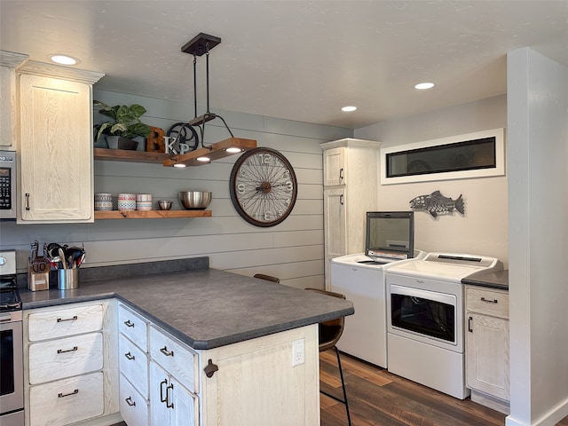 kitchen featuring separate washer and dryer, dark hardwood / wood-style floors, a breakfast bar, pendant lighting, and appliances with stainless steel finishes