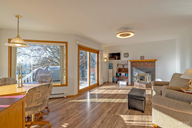 living room featuring hardwood / wood-style flooring, a wood stove, and baseboard heating