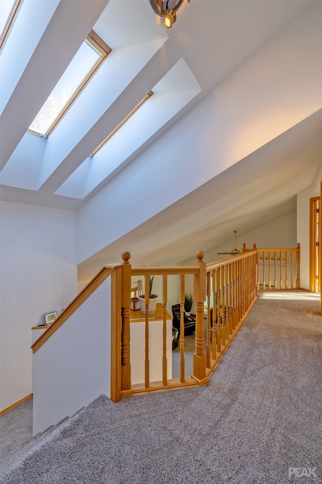 interior space featuring vaulted ceiling with skylight and carpet flooring