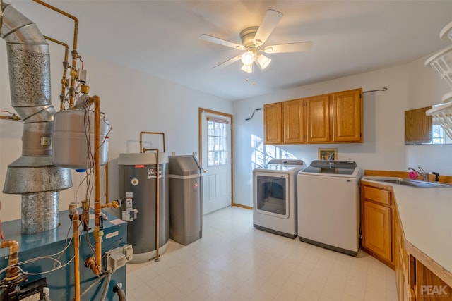 washroom featuring cabinets, sink, washing machine and clothes dryer, ceiling fan, and gas water heater