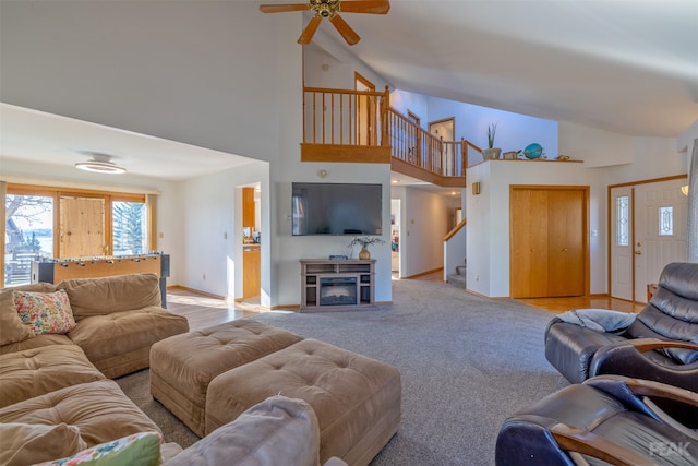 living room featuring high vaulted ceiling, light colored carpet, ceiling fan, and a fireplace