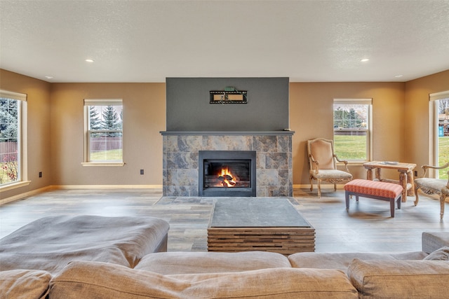 living room with a fireplace, a textured ceiling, and light hardwood / wood-style flooring