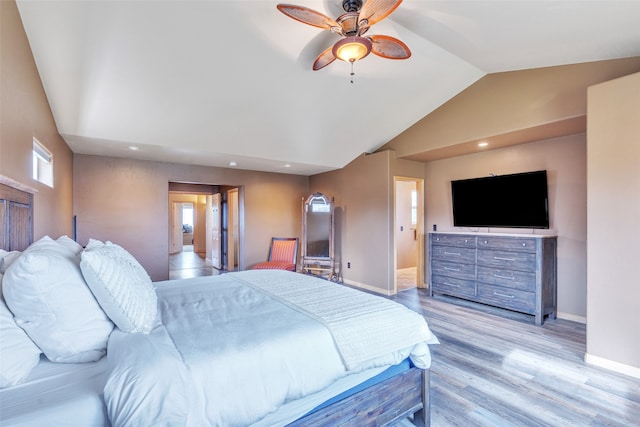 bedroom with ceiling fan, ensuite bath, light wood-type flooring, and vaulted ceiling