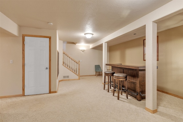 bar featuring carpet and a textured ceiling