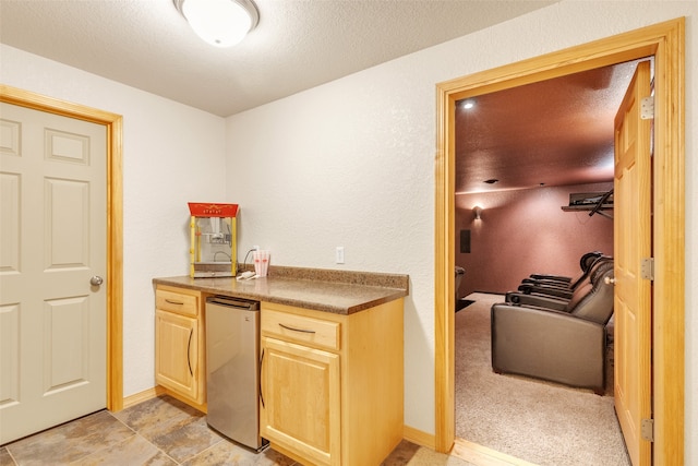 kitchen with light brown cabinets, light colored carpet, a textured ceiling, and stainless steel refrigerator