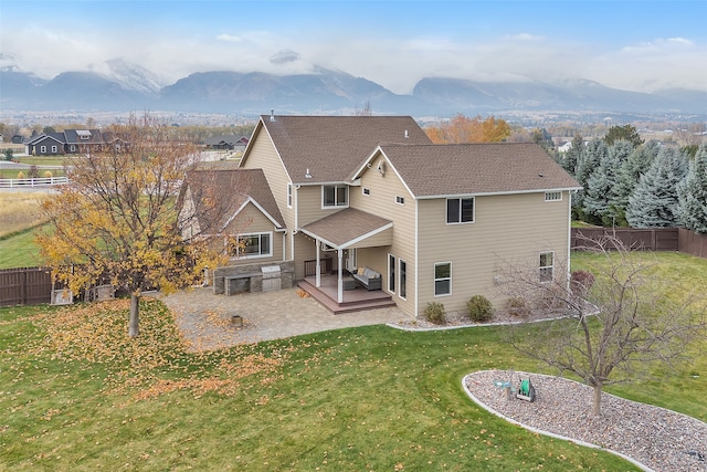 rear view of house featuring a patio, a yard, and a mountain view