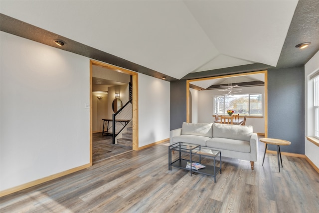 living room featuring lofted ceiling, hardwood / wood-style flooring, and ceiling fan