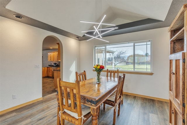 dining room with a notable chandelier, hardwood / wood-style flooring, and lofted ceiling