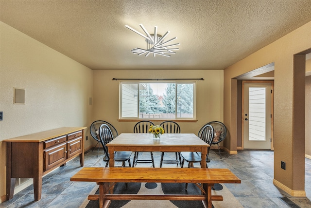 dining space with a textured ceiling and a notable chandelier