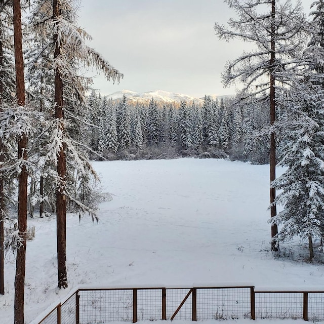 yard covered in snow with fence and a mountain view