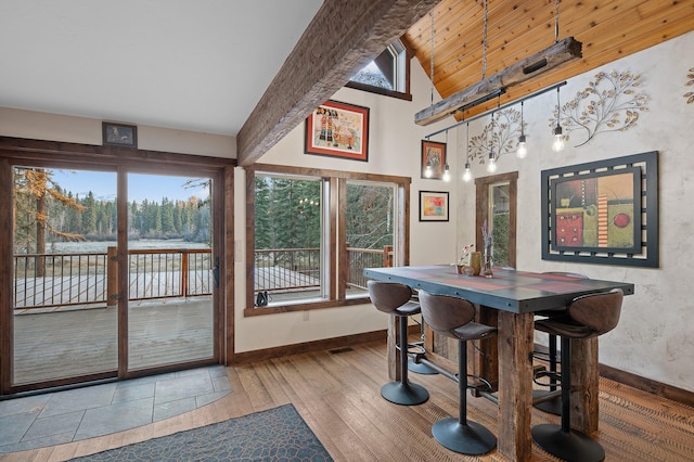 dining room featuring high vaulted ceiling, baseboards, hardwood / wood-style floors, and beamed ceiling