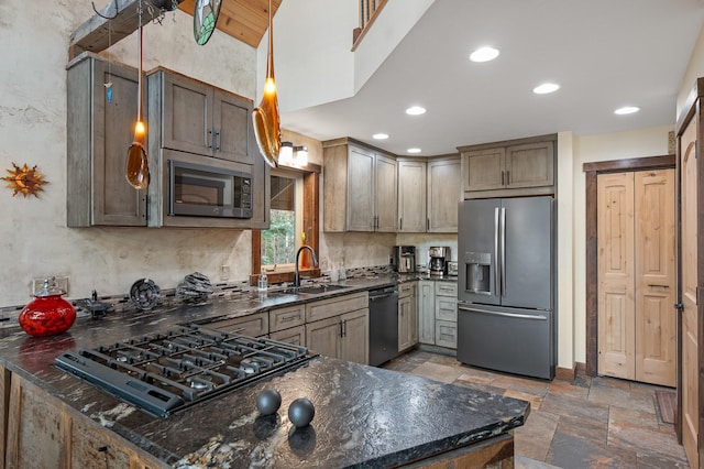 kitchen with decorative light fixtures, stone tile floors, a sink, dark stone countertops, and black appliances