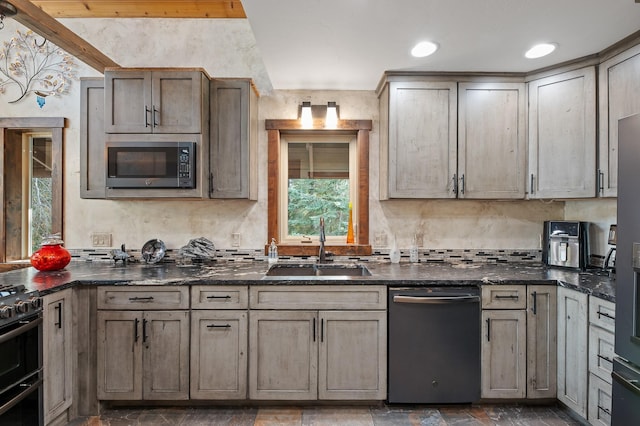 kitchen featuring gas stove, dark stone counters, dishwasher, and a sink