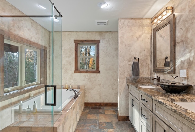 full bath with a garden tub, stone tile floors, a sink, visible vents, and baseboards