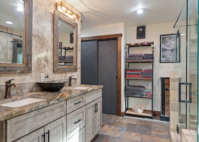 bathroom with a stall shower, stone tile flooring, a sink, and double vanity