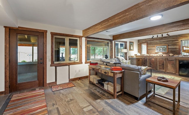 living area with beverage cooler, wooden walls, baseboards, beamed ceiling, and wood finished floors