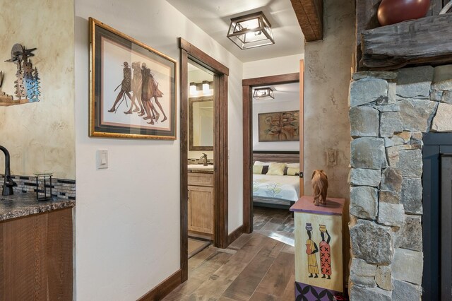 hall featuring dark wood-style flooring, a sink, and baseboards