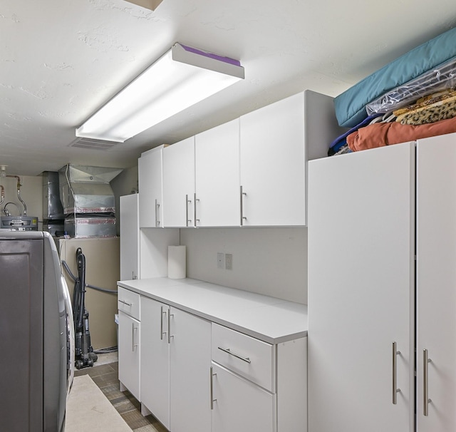 kitchen featuring white cabinets, visible vents, washer / clothes dryer, and light countertops