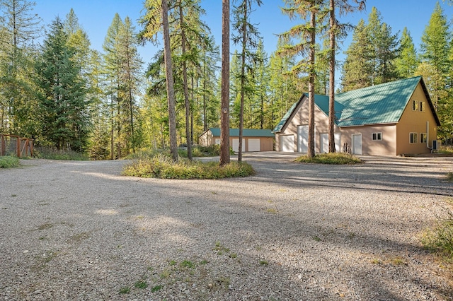 view of front of property featuring a garage, metal roof, and an outbuilding