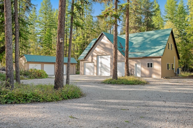 view of front of home featuring gravel driveway, metal roof, and an attached garage