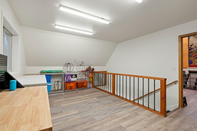 rec room featuring lofted ceiling, a textured ceiling, and wood finished floors