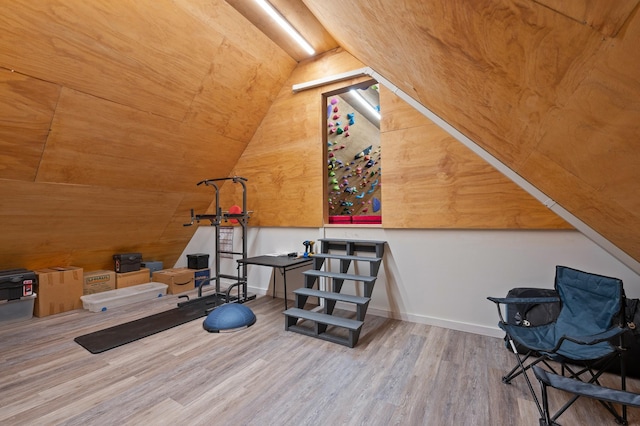 interior space with vaulted ceiling, baseboards, and wood finished floors