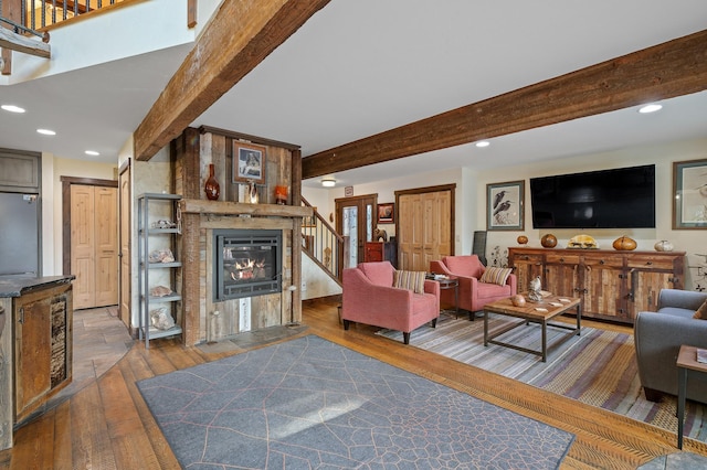 living area with dark wood-style floors, recessed lighting, beamed ceiling, and a glass covered fireplace