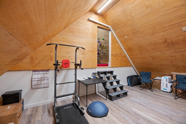 workout room with wooden walls, vaulted ceiling, and wood finished floors