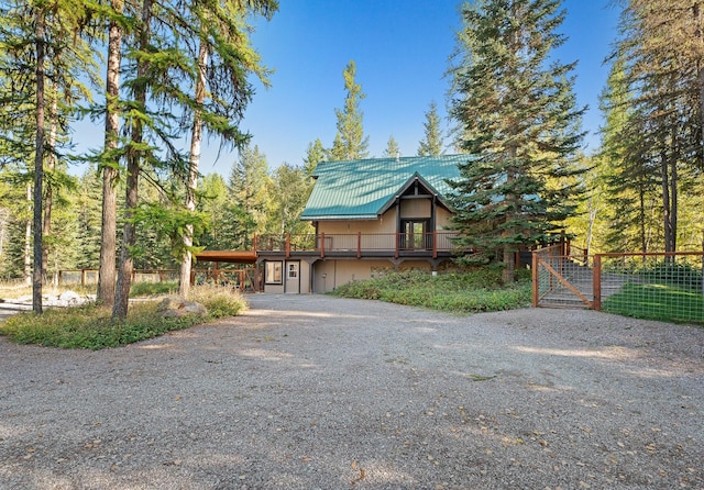 rustic home featuring metal roof, driveway, and a deck