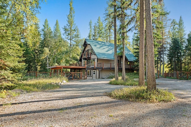 view of front of house with a deck, metal roof, and gravel driveway