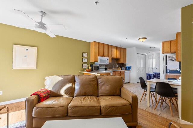 living room featuring light wood-type flooring, sink, and ceiling fan