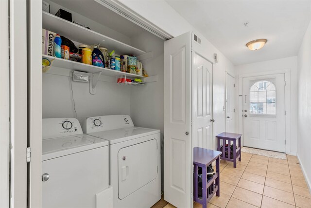 clothes washing area featuring washing machine and clothes dryer and light tile patterned floors