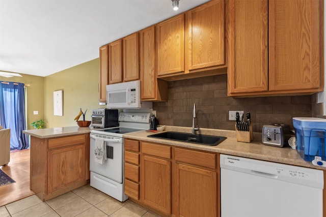 kitchen with kitchen peninsula, sink, tasteful backsplash, light hardwood / wood-style flooring, and white appliances