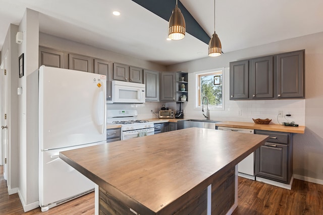 kitchen featuring white appliances, dark hardwood / wood-style floors, hanging light fixtures, and sink